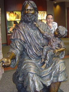 person hiding behind statue of Jesus