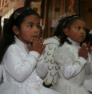 two little girls dressed as angels praying