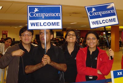 two men and two women holding welcome signs