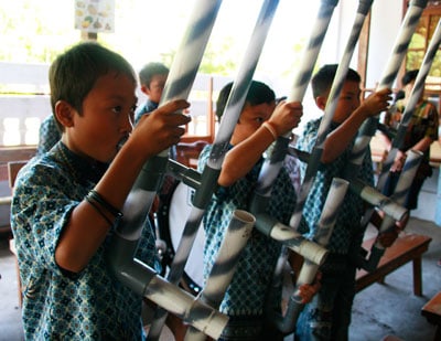 boys playing an instrument made from plastic pipes