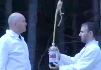 Two men looking at a large bottle of diet coke.