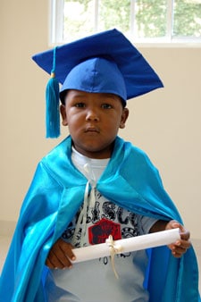 little boy in graduation cap and gown holding a diploma