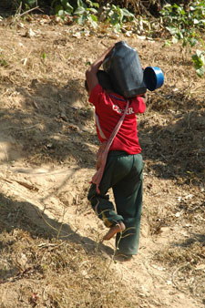 young child carrying a water container on his shoulder