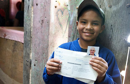 smiling boy holding a letter from his sponsor