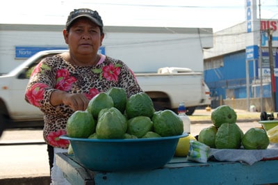 woman in the market standing in front of a bowl of gourds