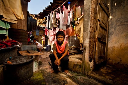 young boy sitting in home with hanging laundry behind him