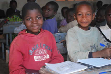 classroom of children with two children writing on paper