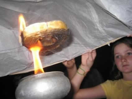 girl looking at fire burning beneath a lantern
