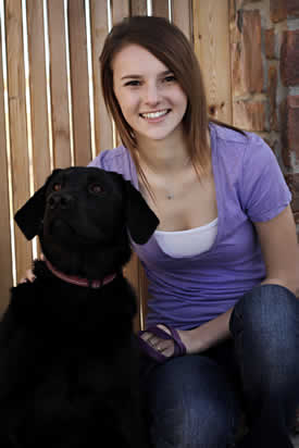 young girl sitting with black dog