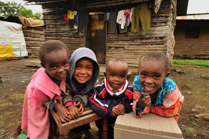 four smiling kids in front of house