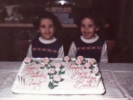 twin girls celebrating birthday with cake