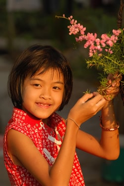 smiling girl in red blouse holding flower