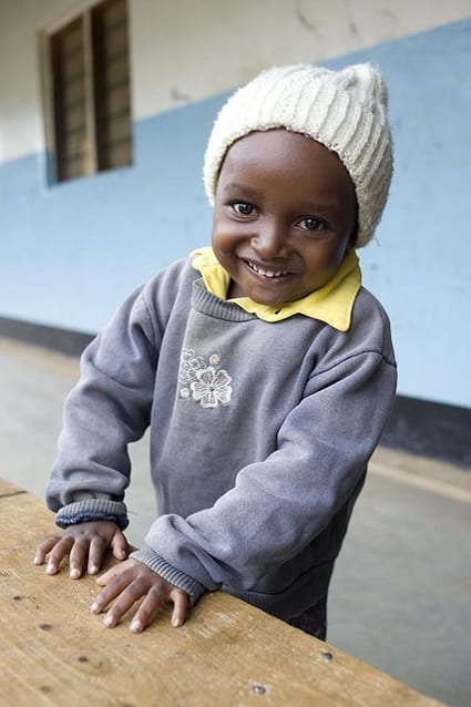 smiling child wearing gray sweater and white knit hat