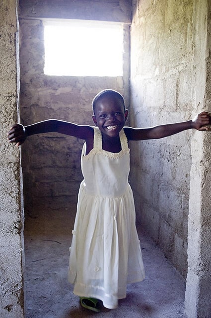 smiling girl in white dress standing in doorway