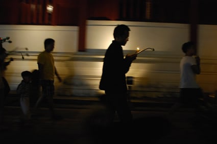 people walking on street holding candles