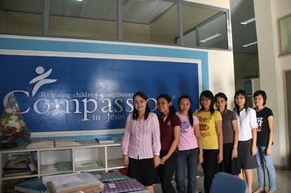 A group of women standing in front of a Compassion International sign