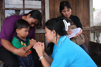 Three women pray with a young boy