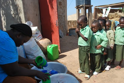 woman washing dishes with children in line