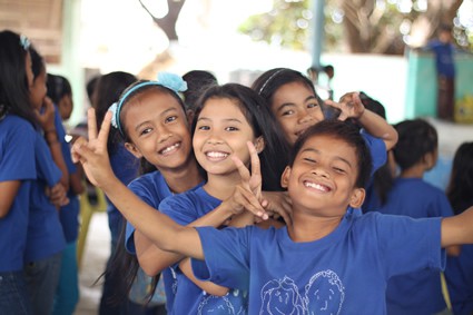 group of smiling children in matching blue shirts