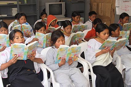 Young girls reading bibles in a classroom.