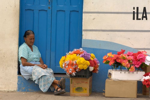 A woman sitting on the ground, selling flowers