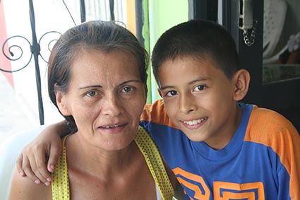 Young boy in Columbia with a blue shirt and his arm around his moms neck showing his great smile after a dentist visit