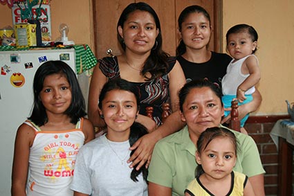 Family of seven all smiling standing in there home in the kitchen