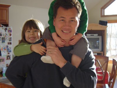 man with two children on his back and shoulders