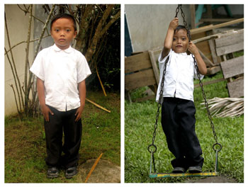 Young boy standing on a swing.