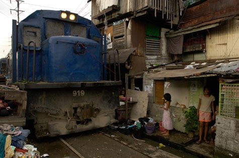 train in a poor neighborhood with two girls in the foreground