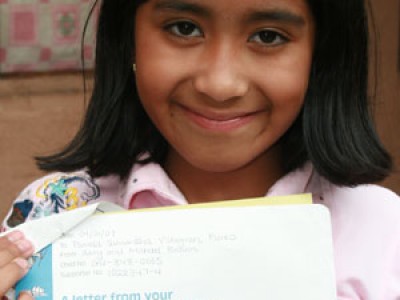 Young smiling girl holding a letter.