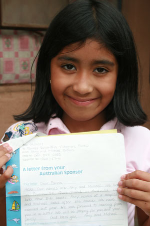 Young smiling girl holding a letter.