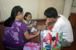 man and woman with small child opening gifts