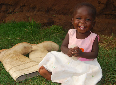 smiling baby sitting next to a pair of boots