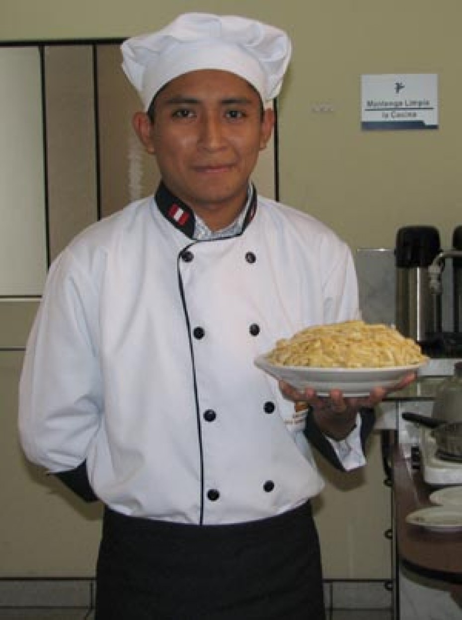 man in chef's uniform holding bowl of pasta