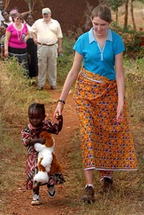 woman walking with small child with people looking on in background