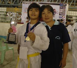 mother and daughter holding up medal and trophy for martial arts