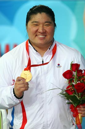 woman wearing gold medal and holding roses
