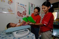 two women weighing baby on scale