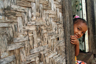 Young child looking out from behind a wall.