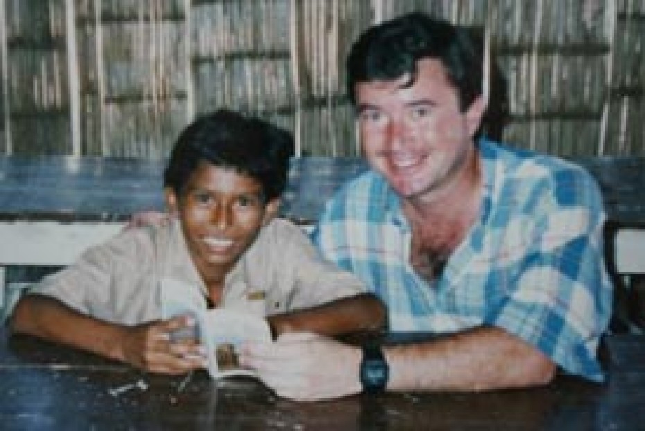 A man and a boy sitting at a table looking at a book