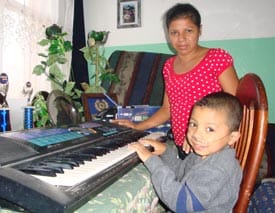 woman standing by boy playing the piano