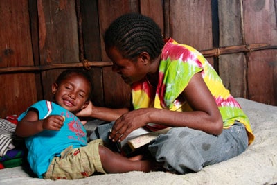 woman sitting on bed with young boy