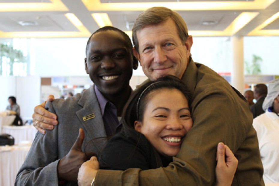 Wess Stafford embracing man and woman