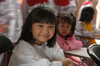 smiling girl with tinsel in her hair with another girl looking on
