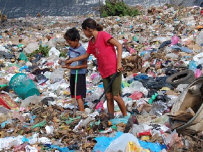 two children standing in garbage dump