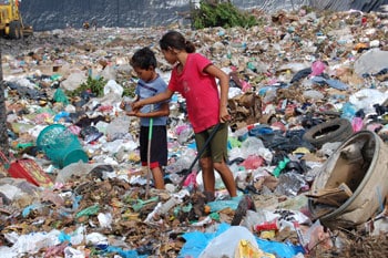 two children standing in garbage dump