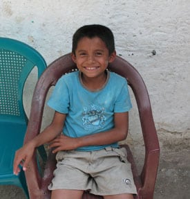 young smiling boy sitting in plastic chair