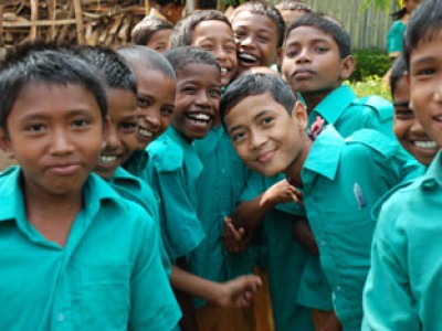 A group of smiling children in teal shirts