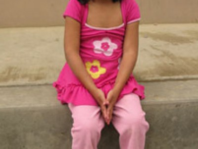 little girl dressed in pink sitting on a step